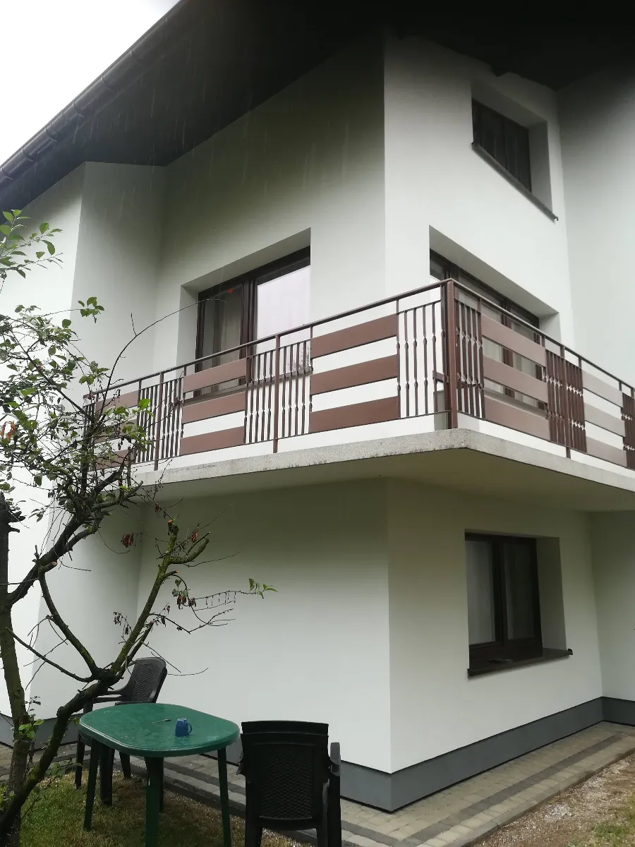 Elewacje domu z nowym balkonem i brązowymi ramami okien