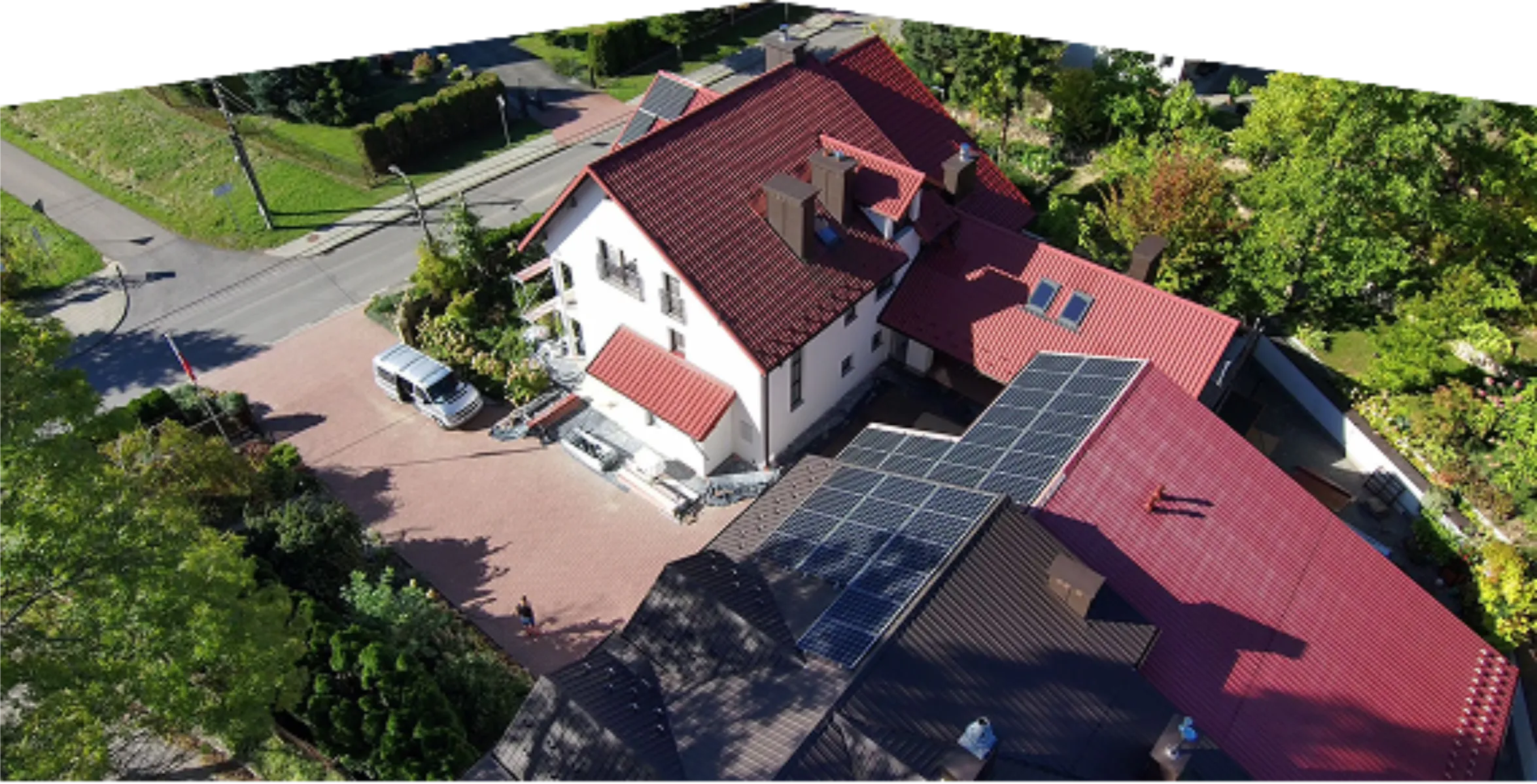 Elewacje domu: widok z lotu ptaka na budynek z czerwoną dachówką, białą elewacją i panelami słonecznymi