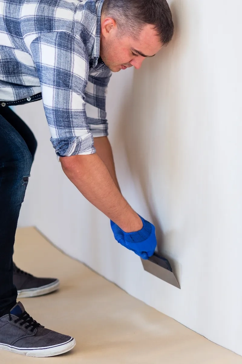 Nakładanie gładzi na ścianę szpachelką przez pracownika