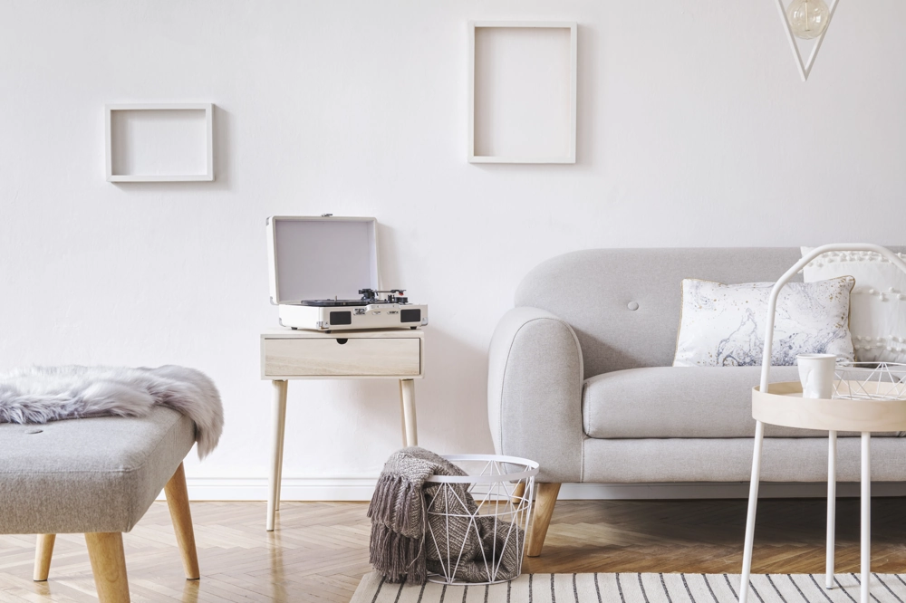 Nowoczesna aranżacja wnętrza z szarą sofą, stolikiem, gramofonem i drewnianymi elementami